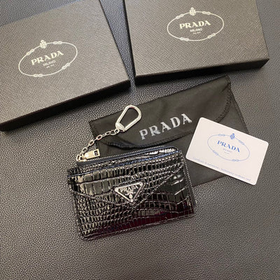A person's hand holding a PRADA Classic Card Holder Wallet with keys attached to its durable chain.