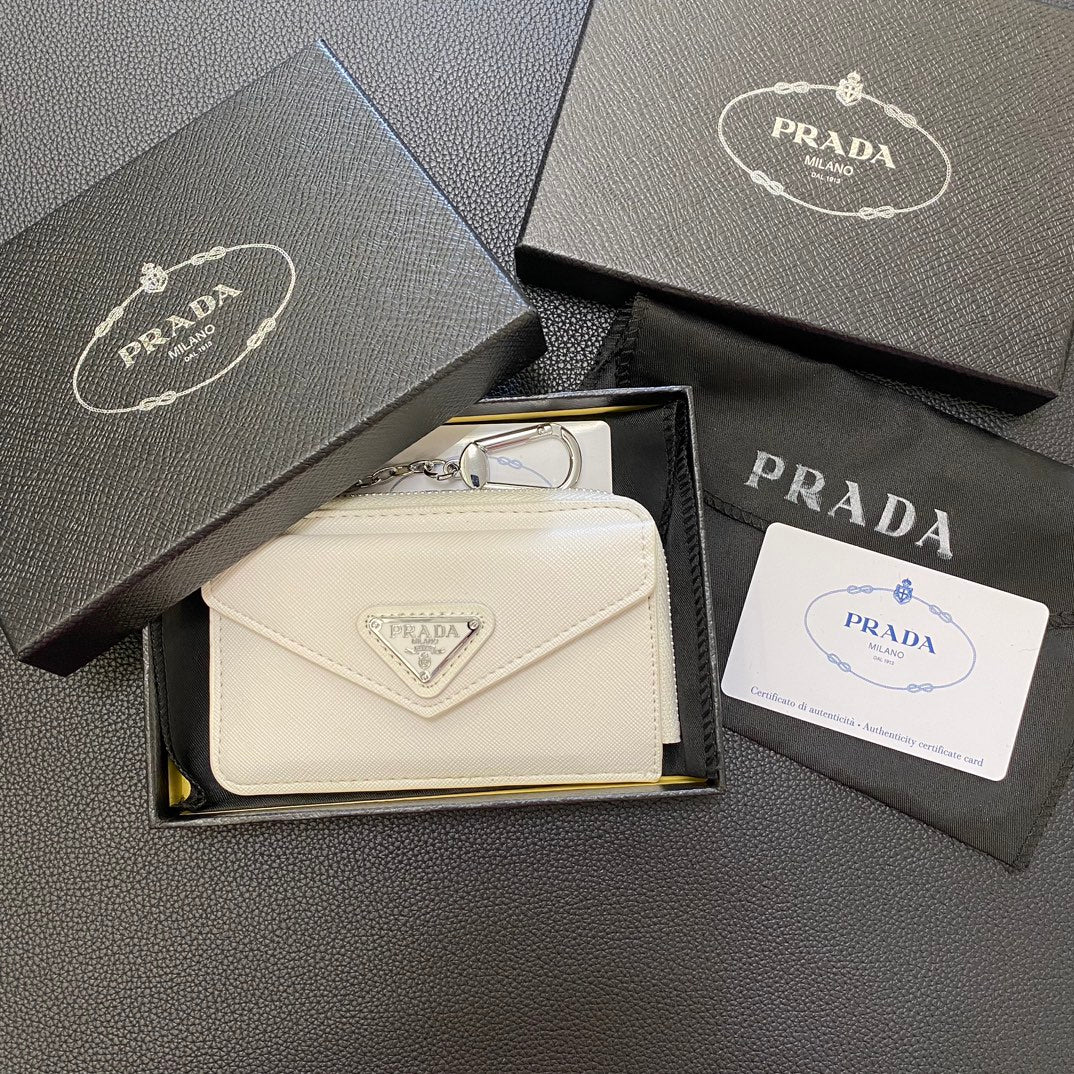 A hand sliding cards into the card slots of a sleek PRADA Classic Card Holder Wallet.